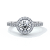 Platinum ring with a one and a half carat round diamond secured in four claws with a halo setting around the center diamond